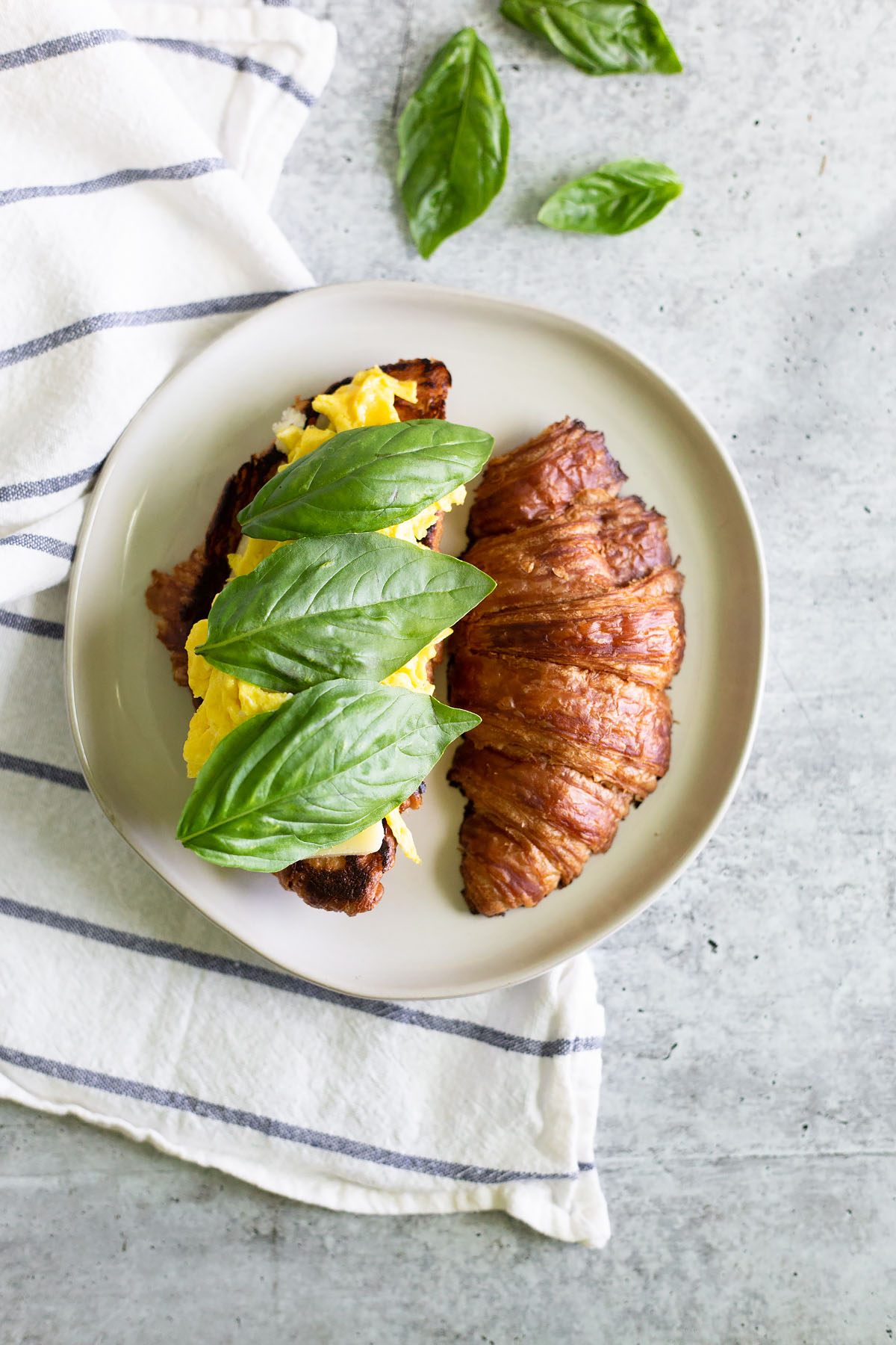croissant breakfast sandwich with basil and scrambled eggs