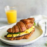 croissant breakfast sandwich with eggs and basil