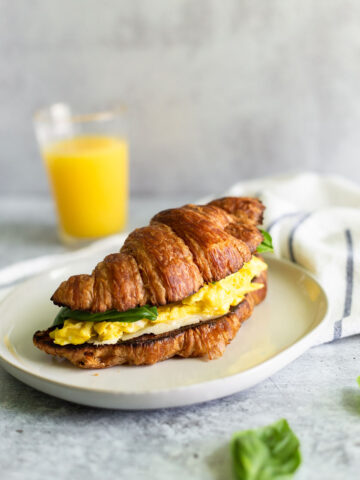 croissant breakfast sandwich with eggs and basil