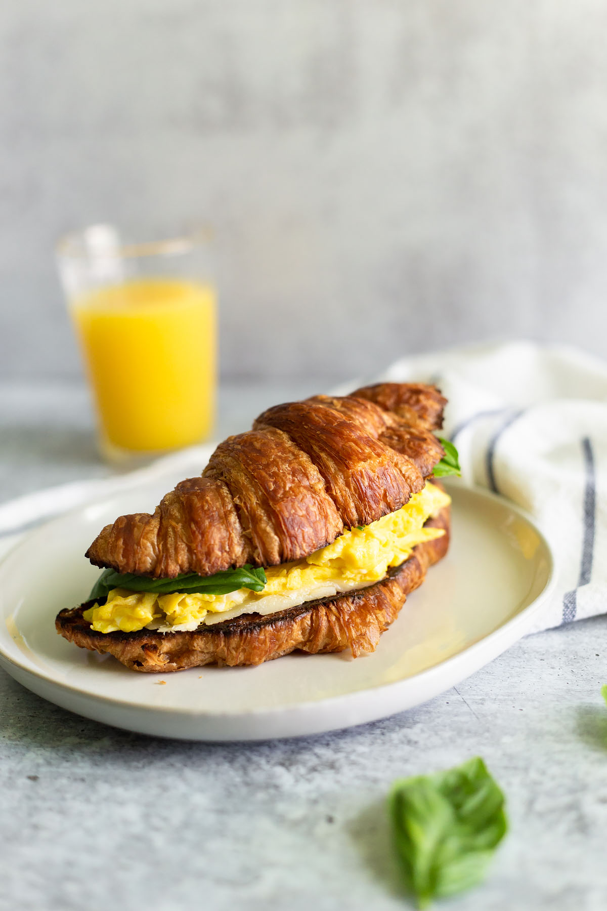 croissant breakfast sandwich with eggs and basil