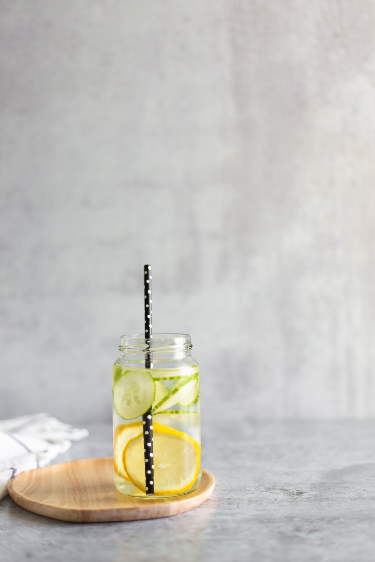 cucumbers and lemons in a jar with water and a straw