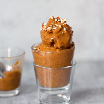 pumpkin banana ice cream in a glass topped with pecans