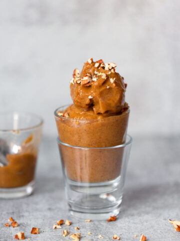 pumpkin banana ice cream in a glass topped with pecans