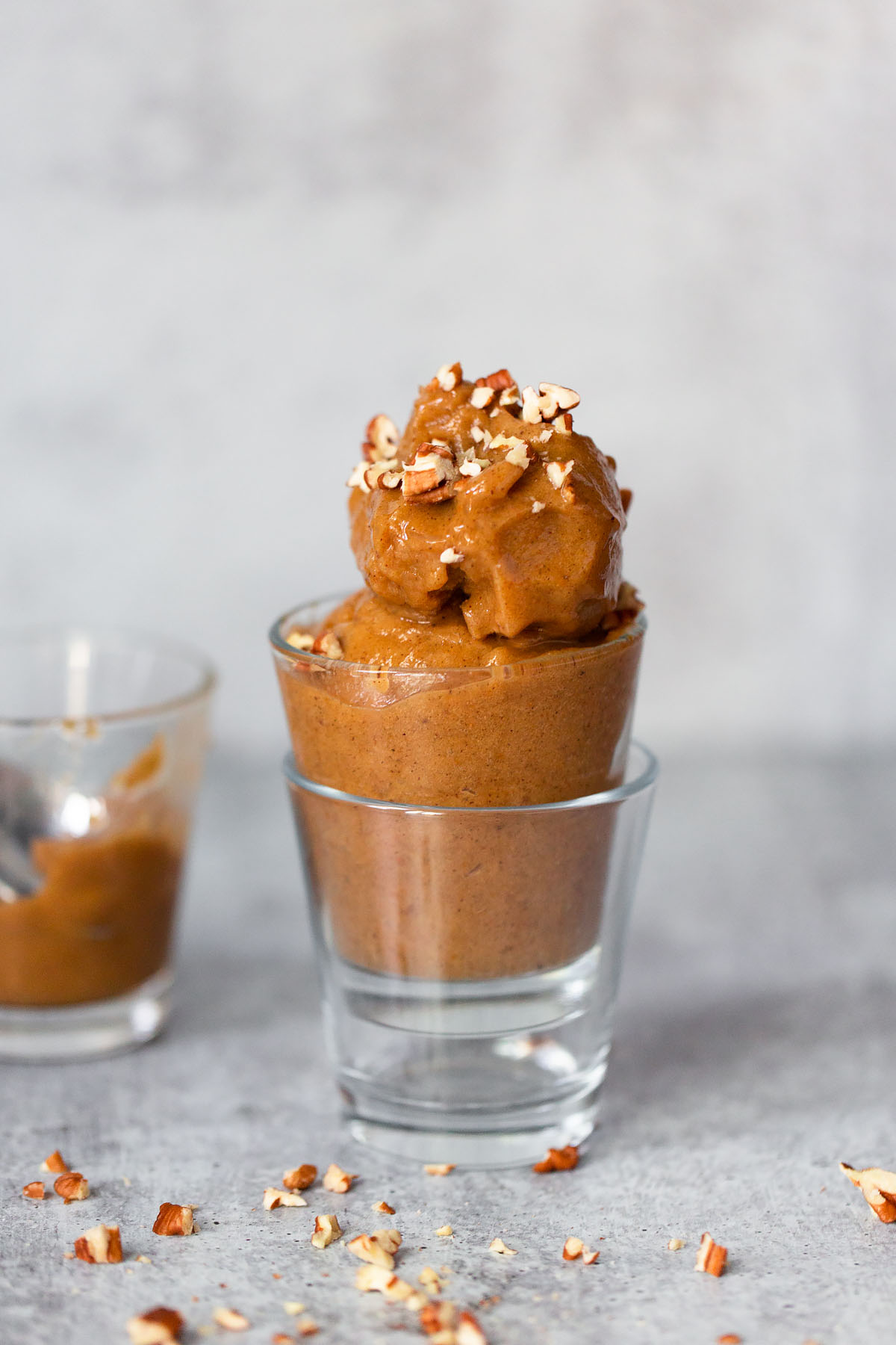 pumpkin banana ice cream in a glass topped with pecans