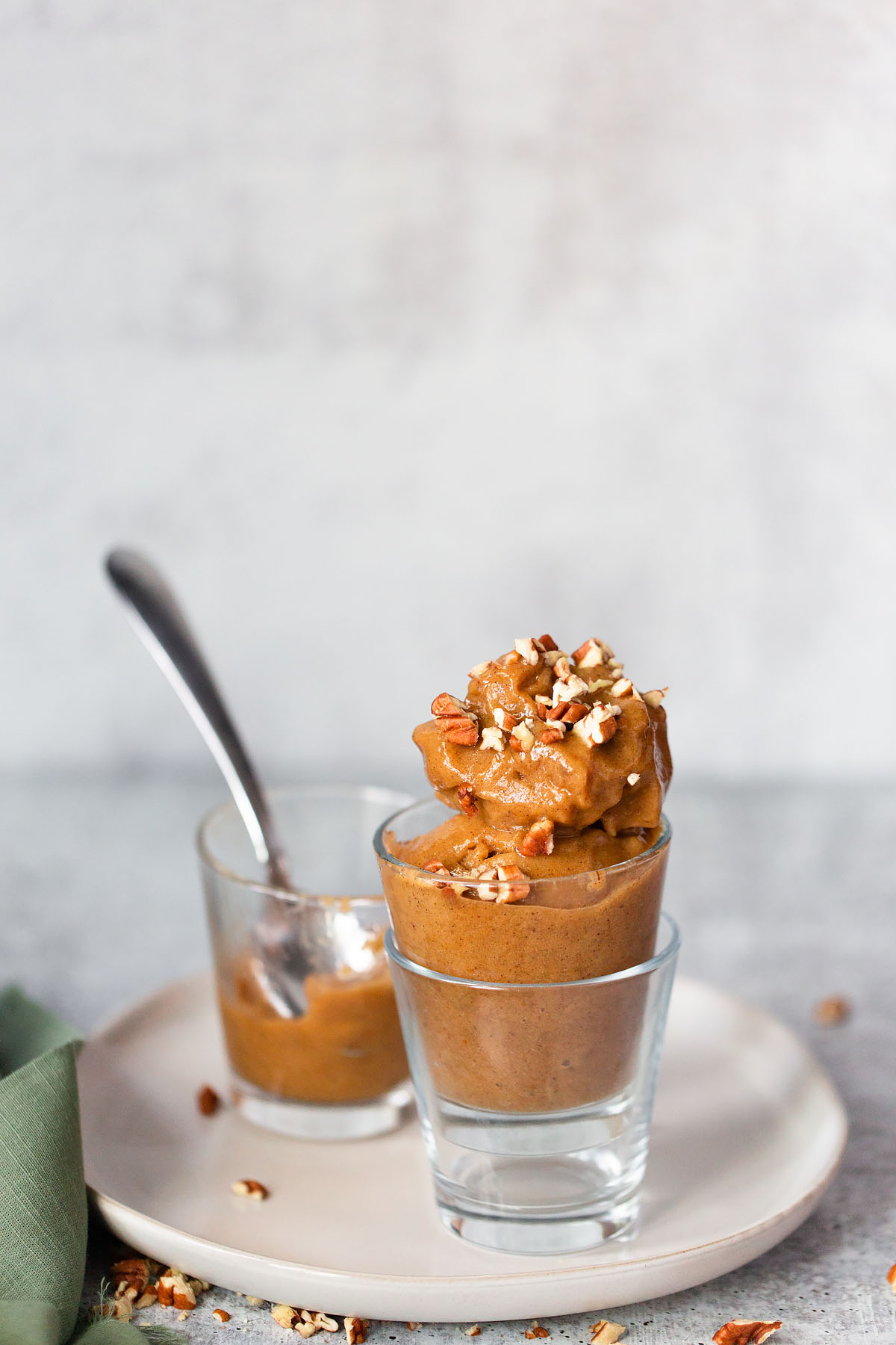 pumpkin banana ice cream in a glass topped with chopped pecans