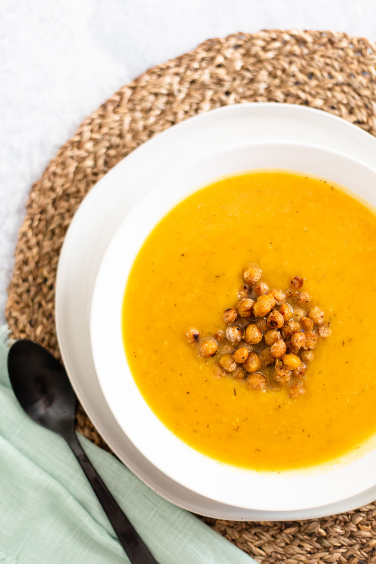 butternut squash soup in a white bowl topped with roasted chickpeas