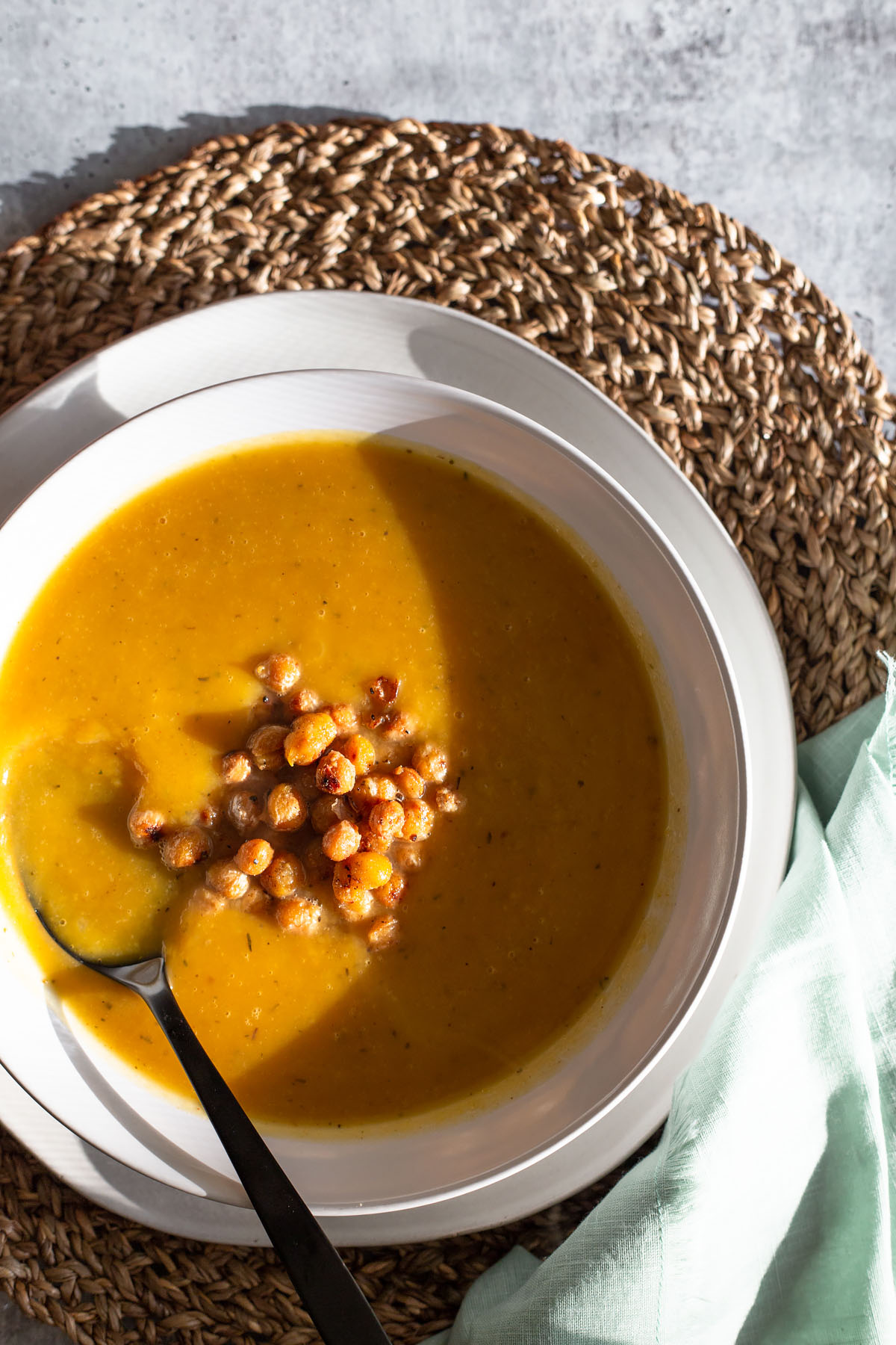 butternut squash soup with chickpeas in a white bowl and black spoon