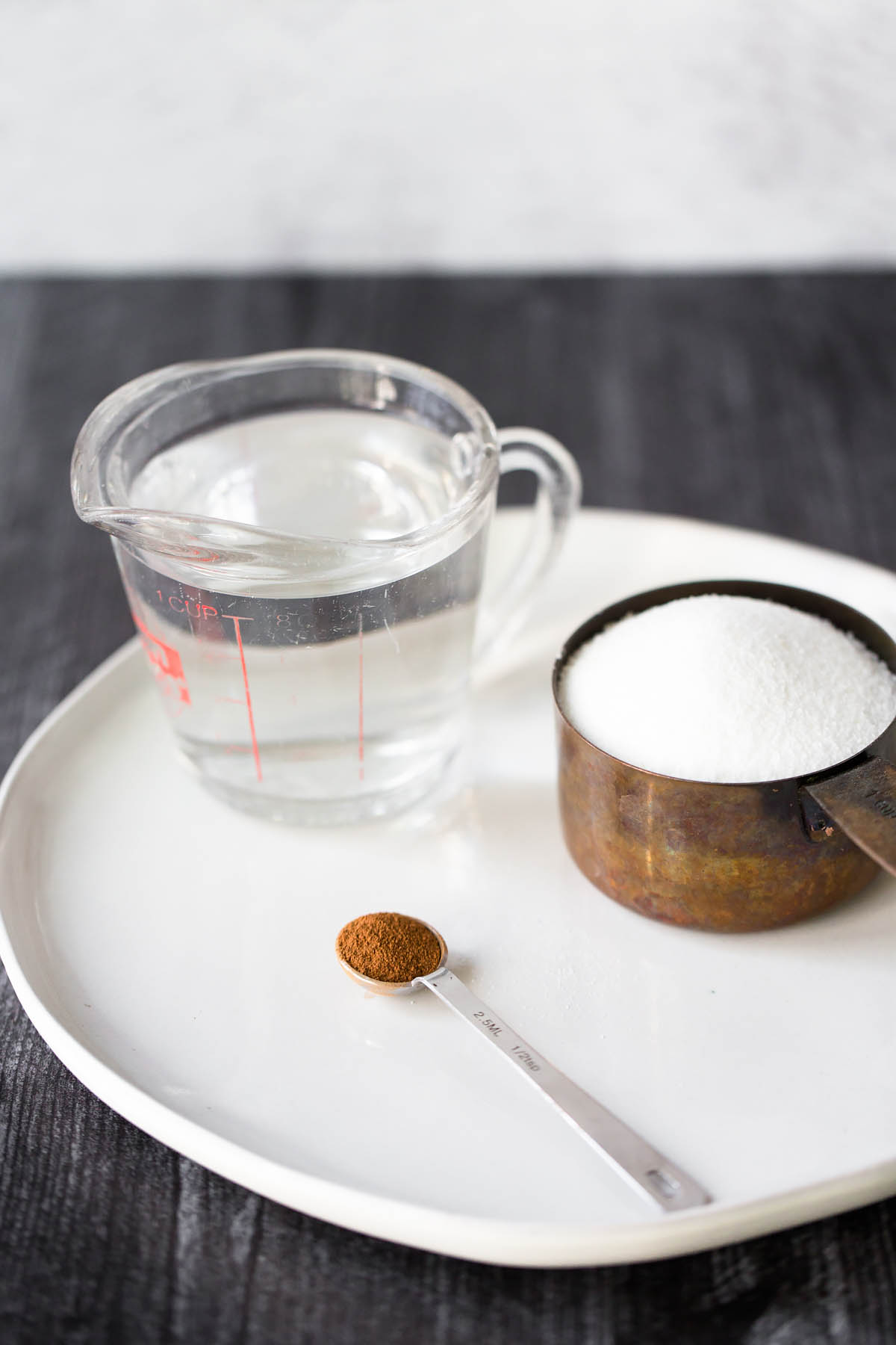 White cup of coffee and cinnamon tubes, spoon with ground coffee