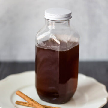 cinnamon simple syrup in a jar with cinnamon sticks on the side