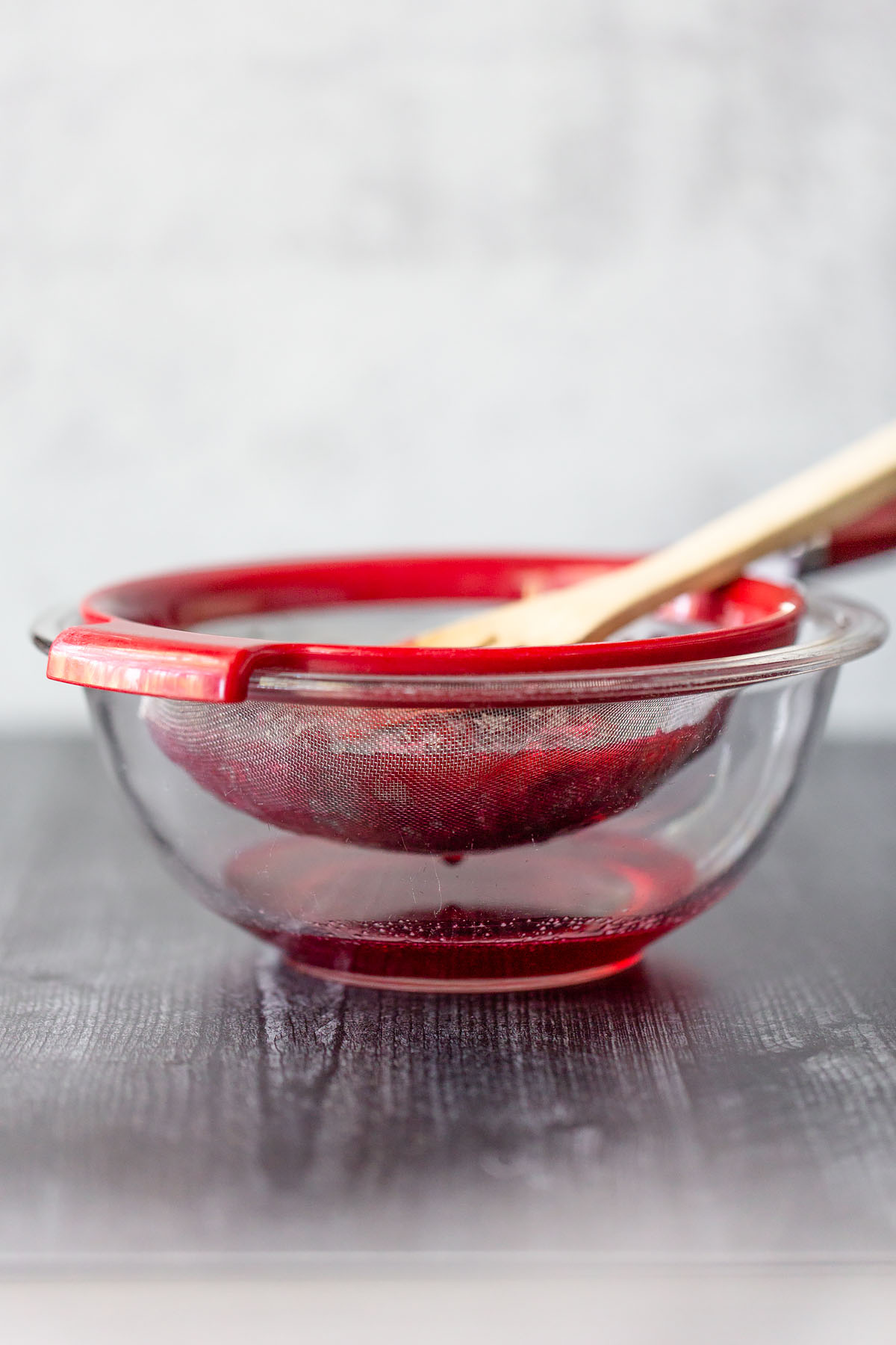 pushing cooked cranberries through a mesh strainer