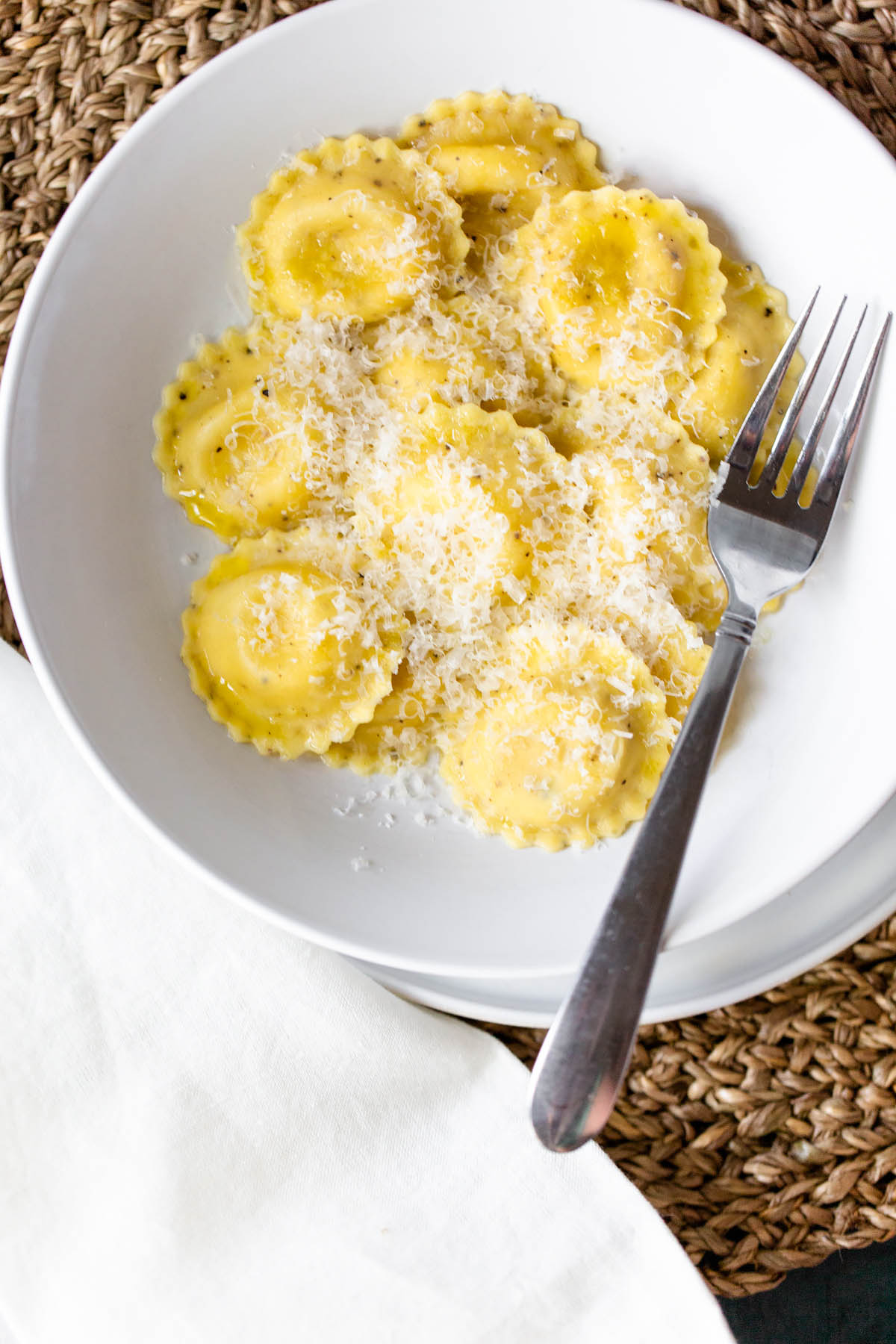 trader joes caico e pepe ravioli cooked and on a plate topped with parmesan cheese