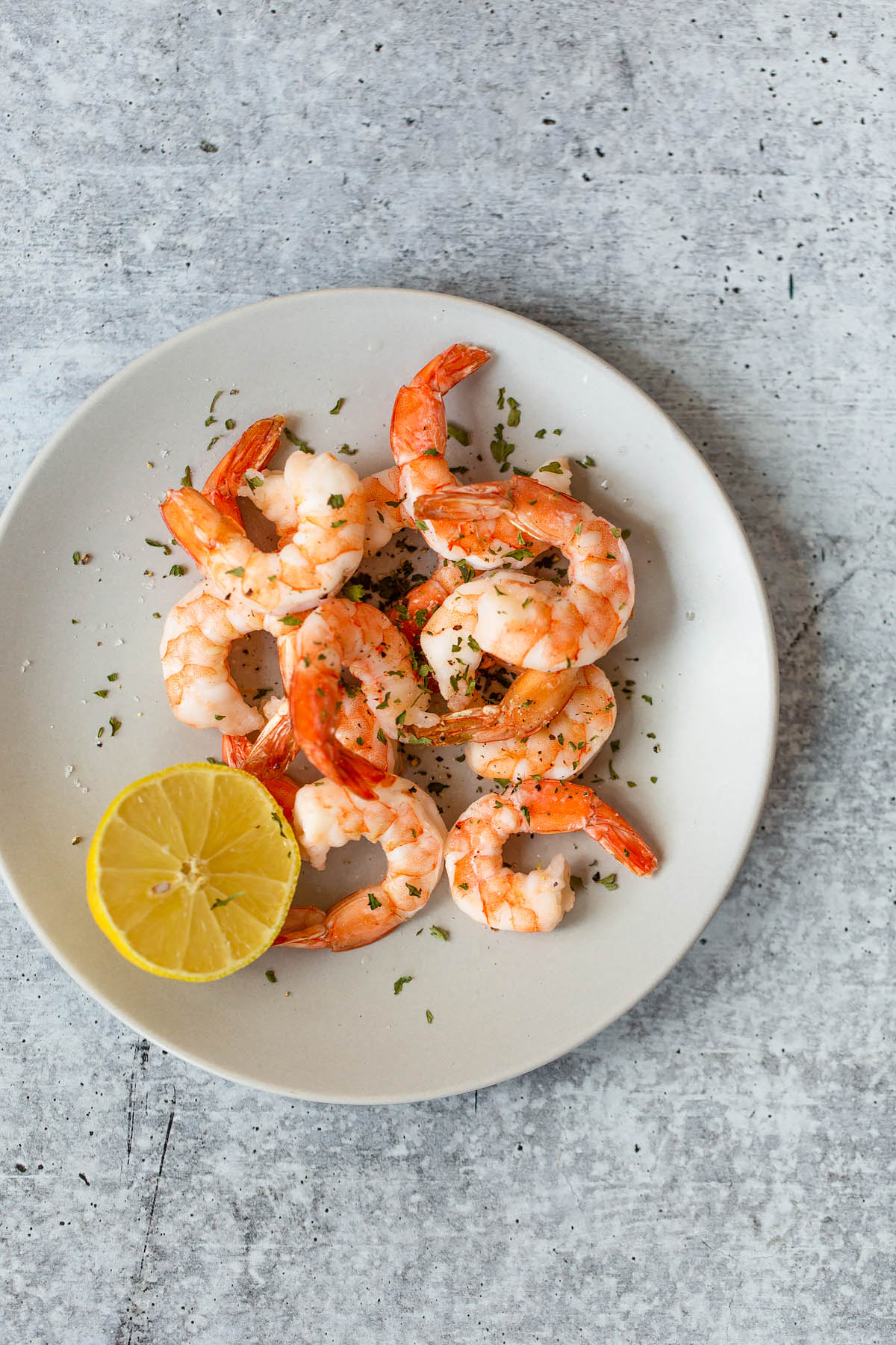 cooked shrimp on a plate with a lemon half