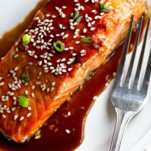 Air fryer teriyaki salmon topped with sesame seeds and green onions.
