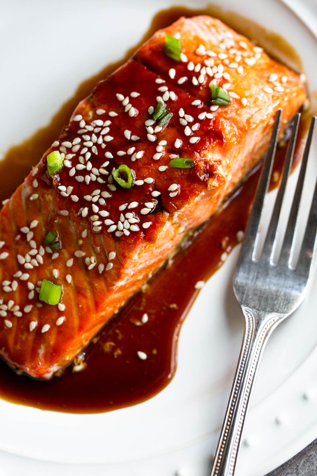 Air fryer teriyaki salmon topped with sesame seeds and green onions.