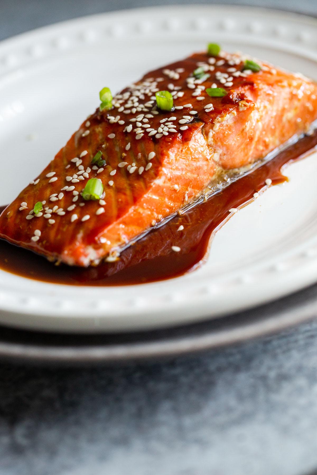 Air fryer teriyaki salmon topped with sesame seeds and green onions.