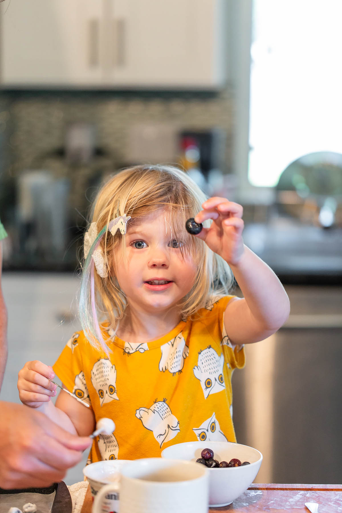 girl holding up a blueberry