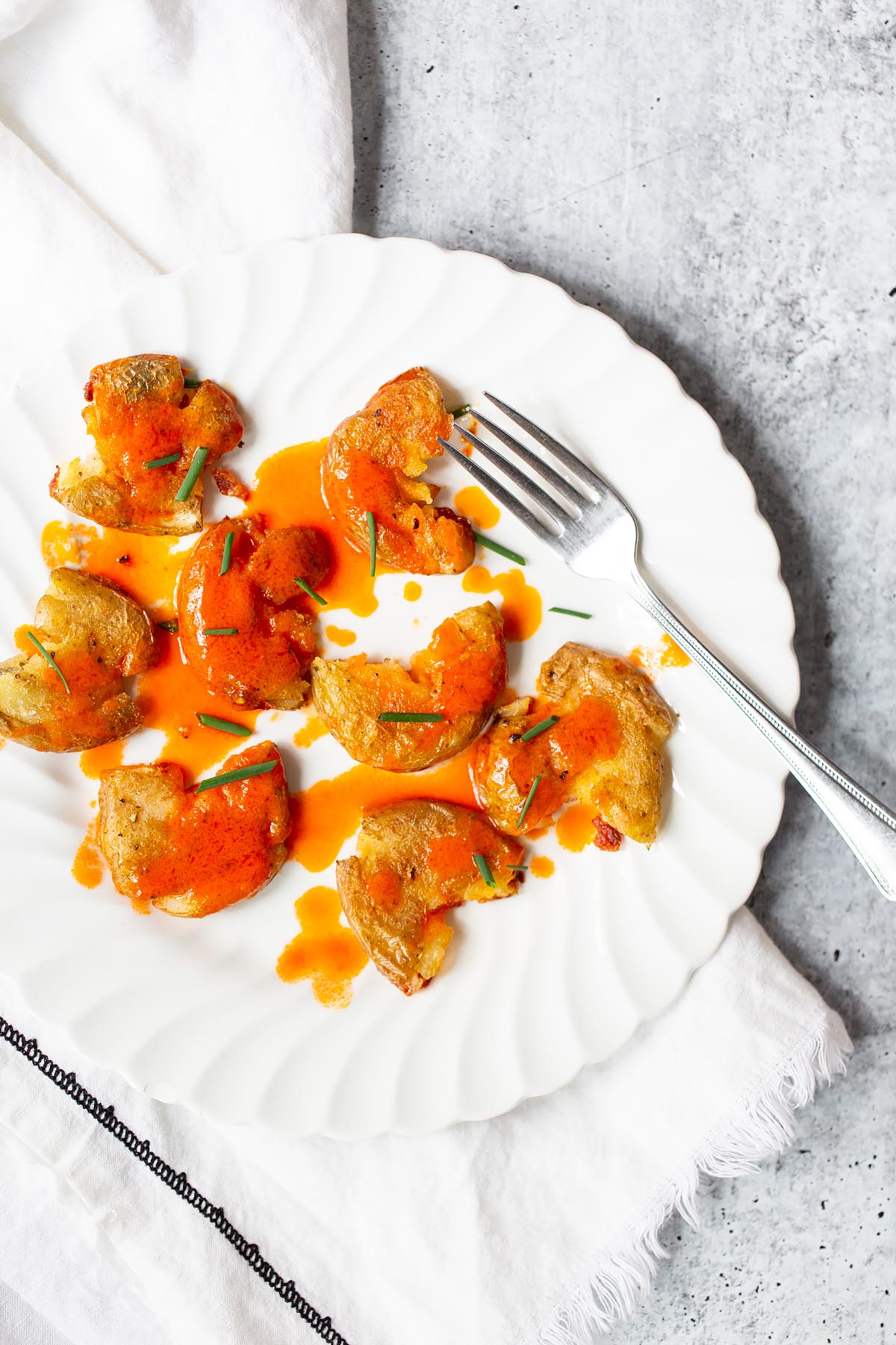 buffalo smashed potatoes on a plate with chives