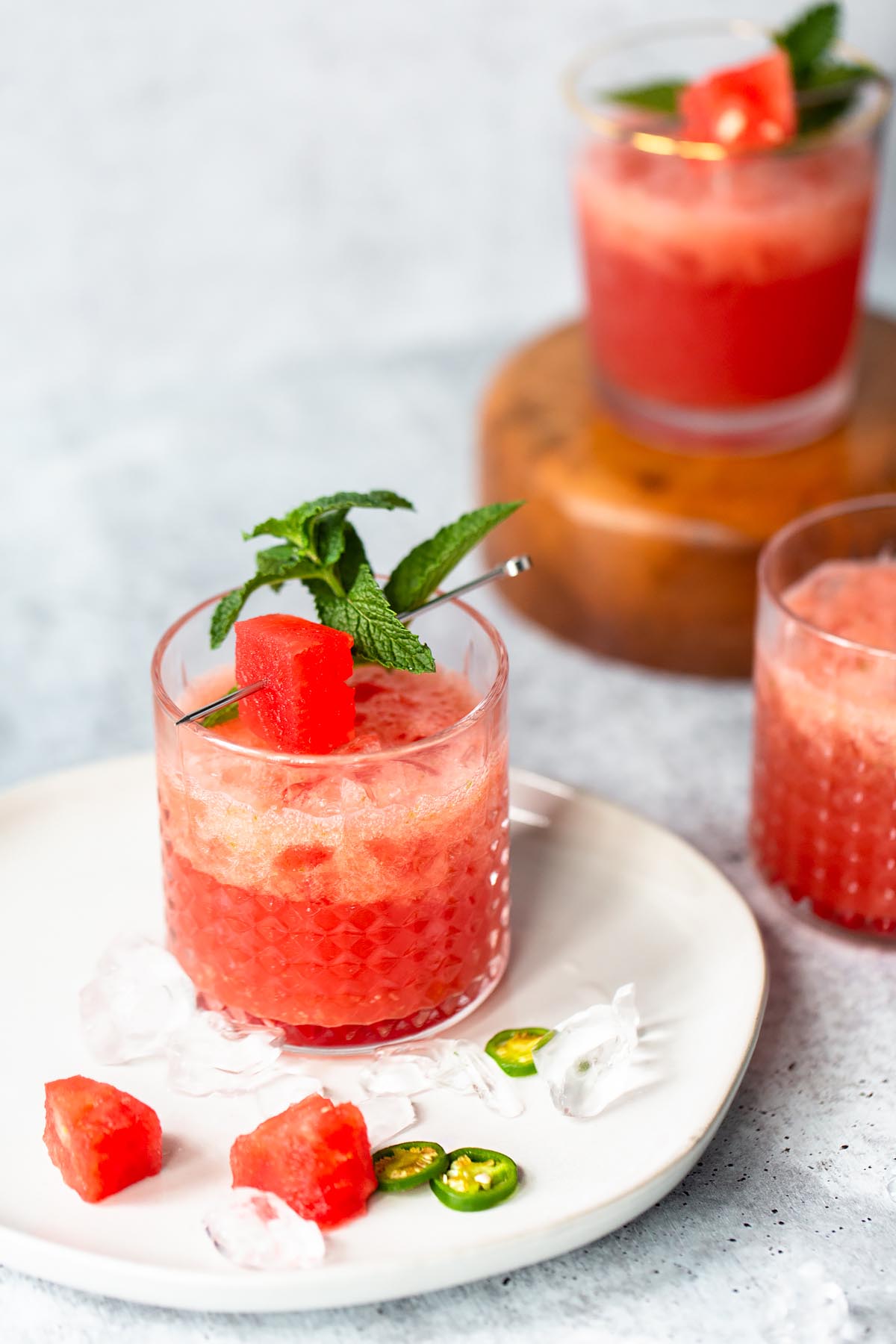 watermelon jalapeno drink on a plate with a watermelon and mint garlnish