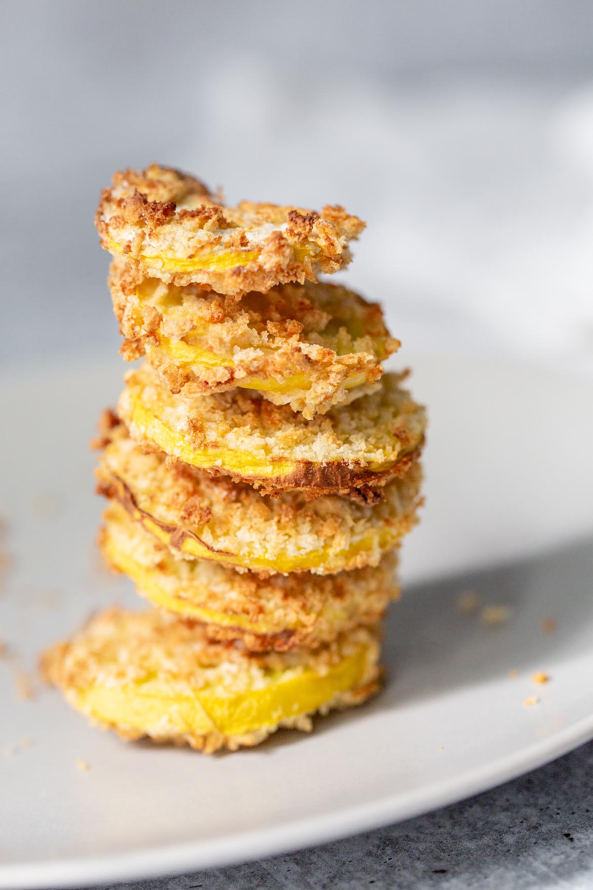 stacked air fried squash on a plate with panko breadcrumbs