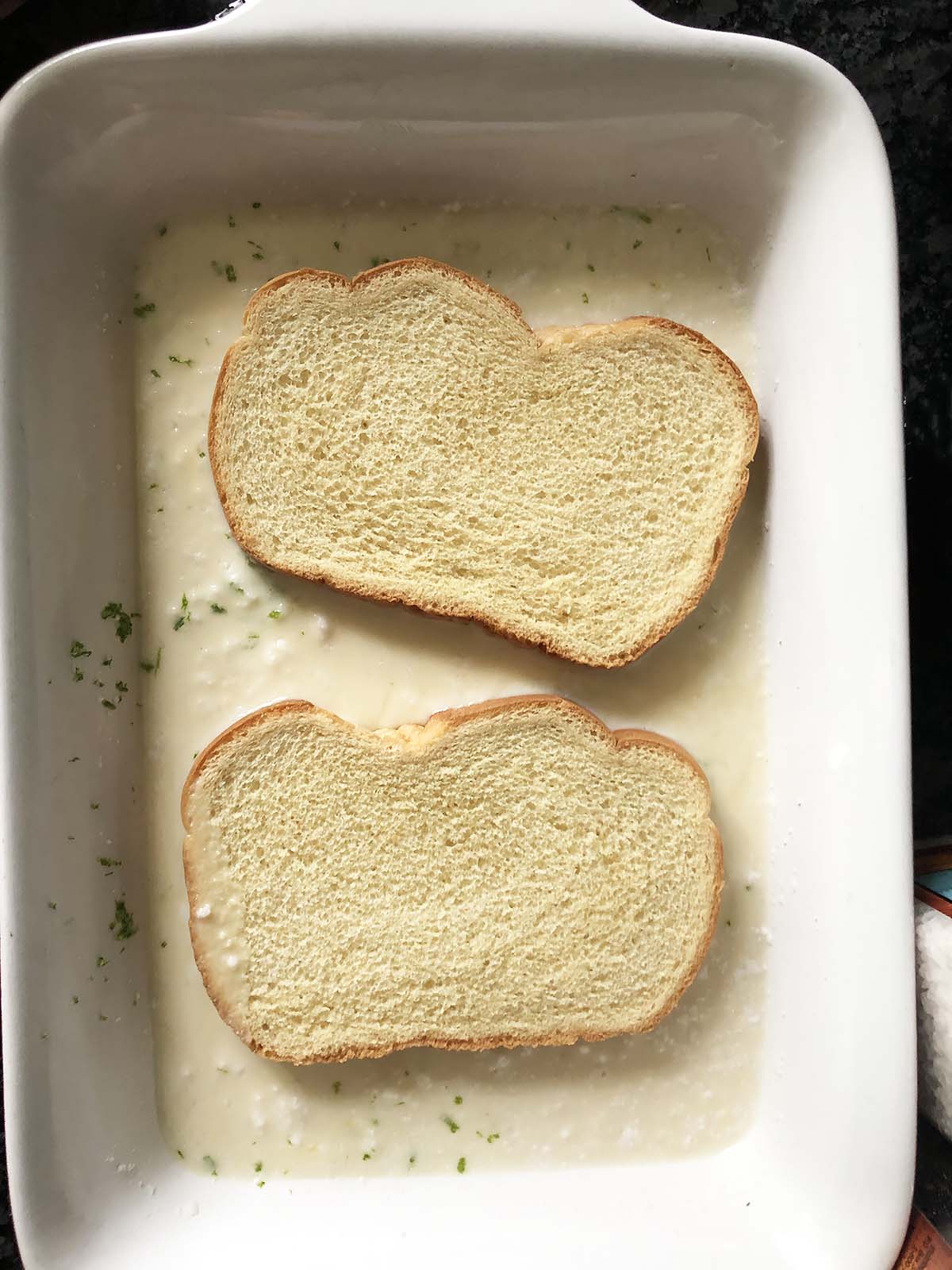 two slices of bread soaking in french toast batter