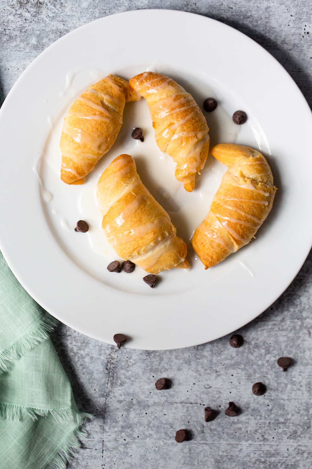 four chocolate croissants on a plate with chocolate chips