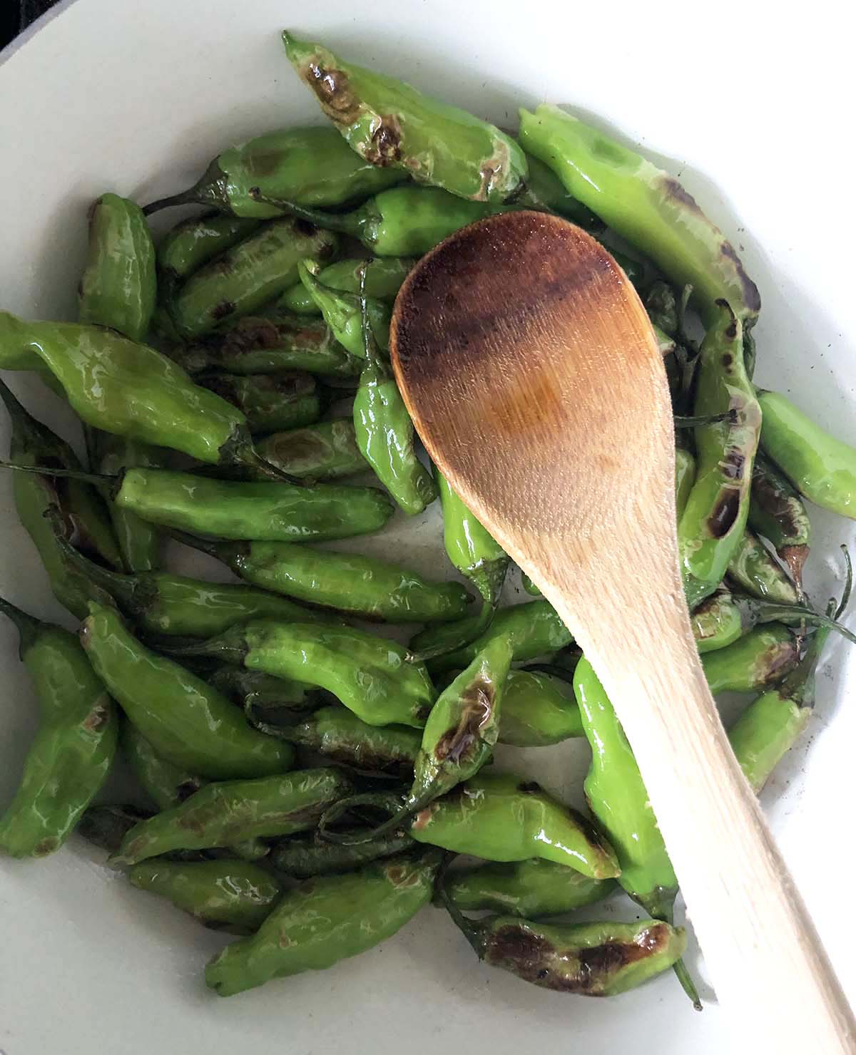 shishito peppers cooking in a skillet