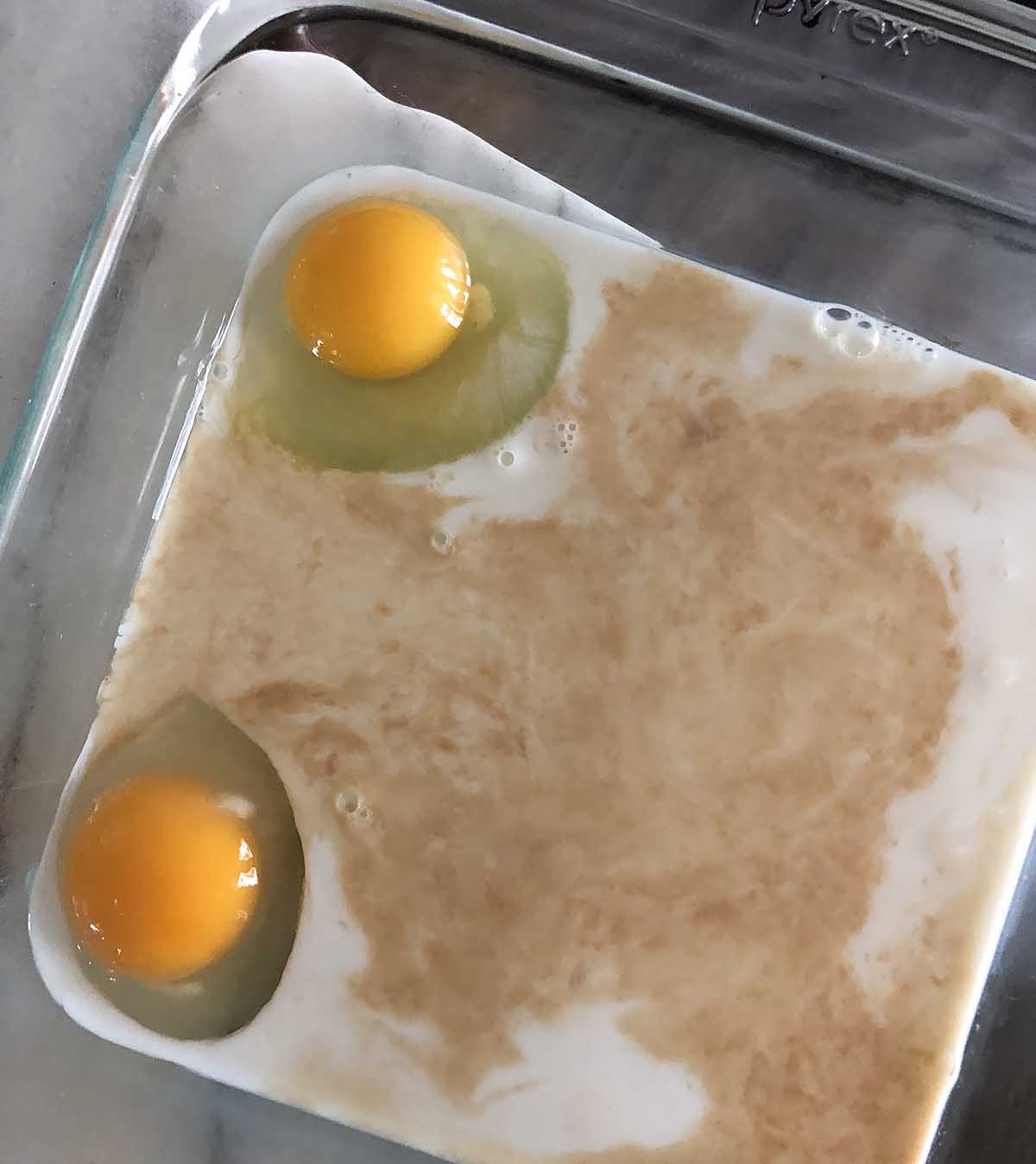 two cracked eggs in milk with vanilla