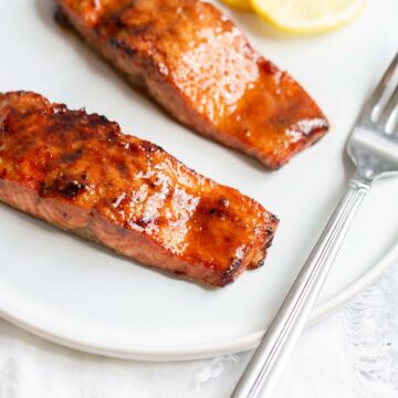 Two pieces of cooked salmon with lemon slices.