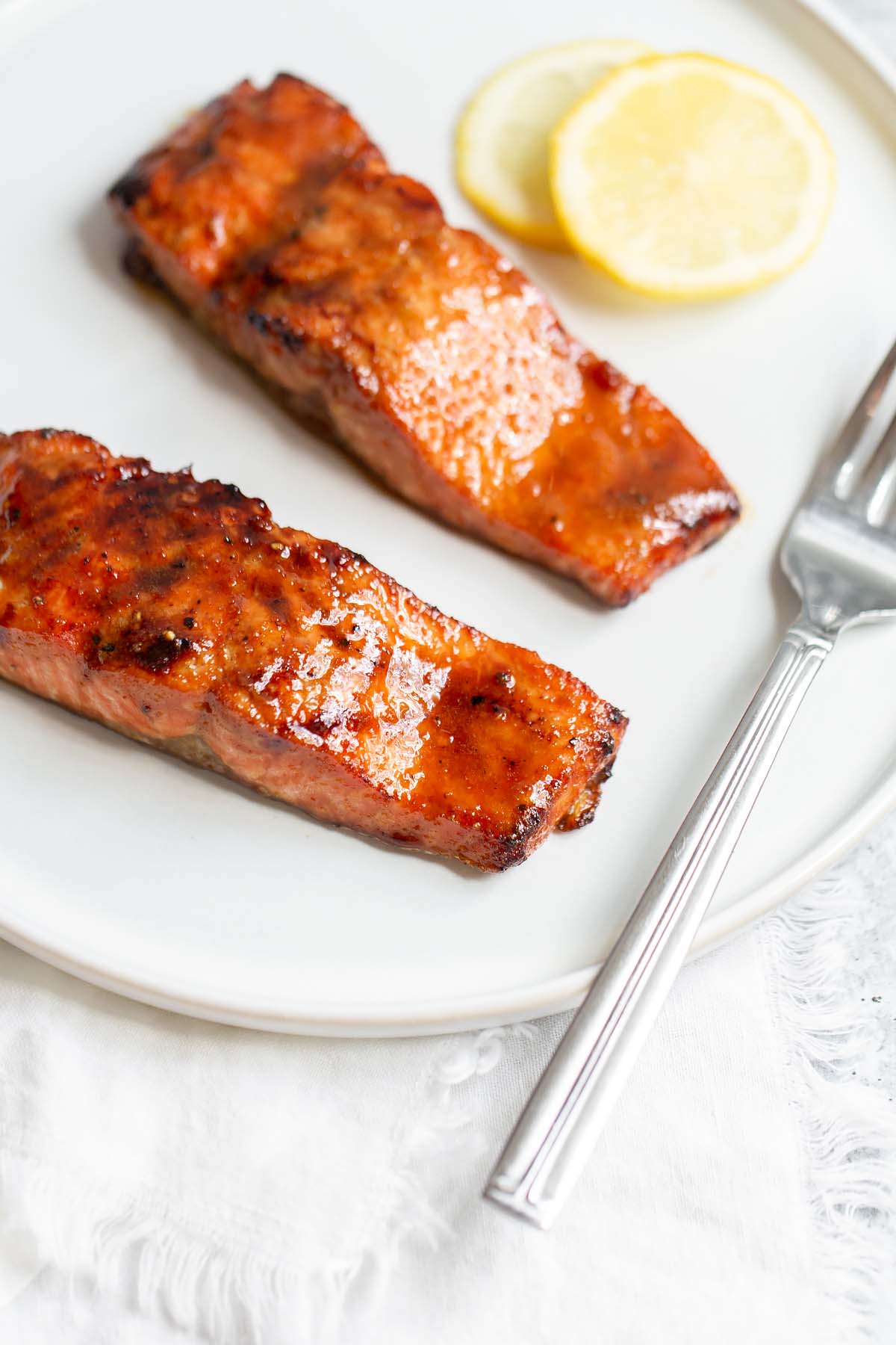 Two pieces of cooked salmon with lemon slices.