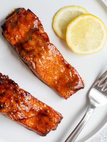 Two pieces of cooked salmon with lemon slices.