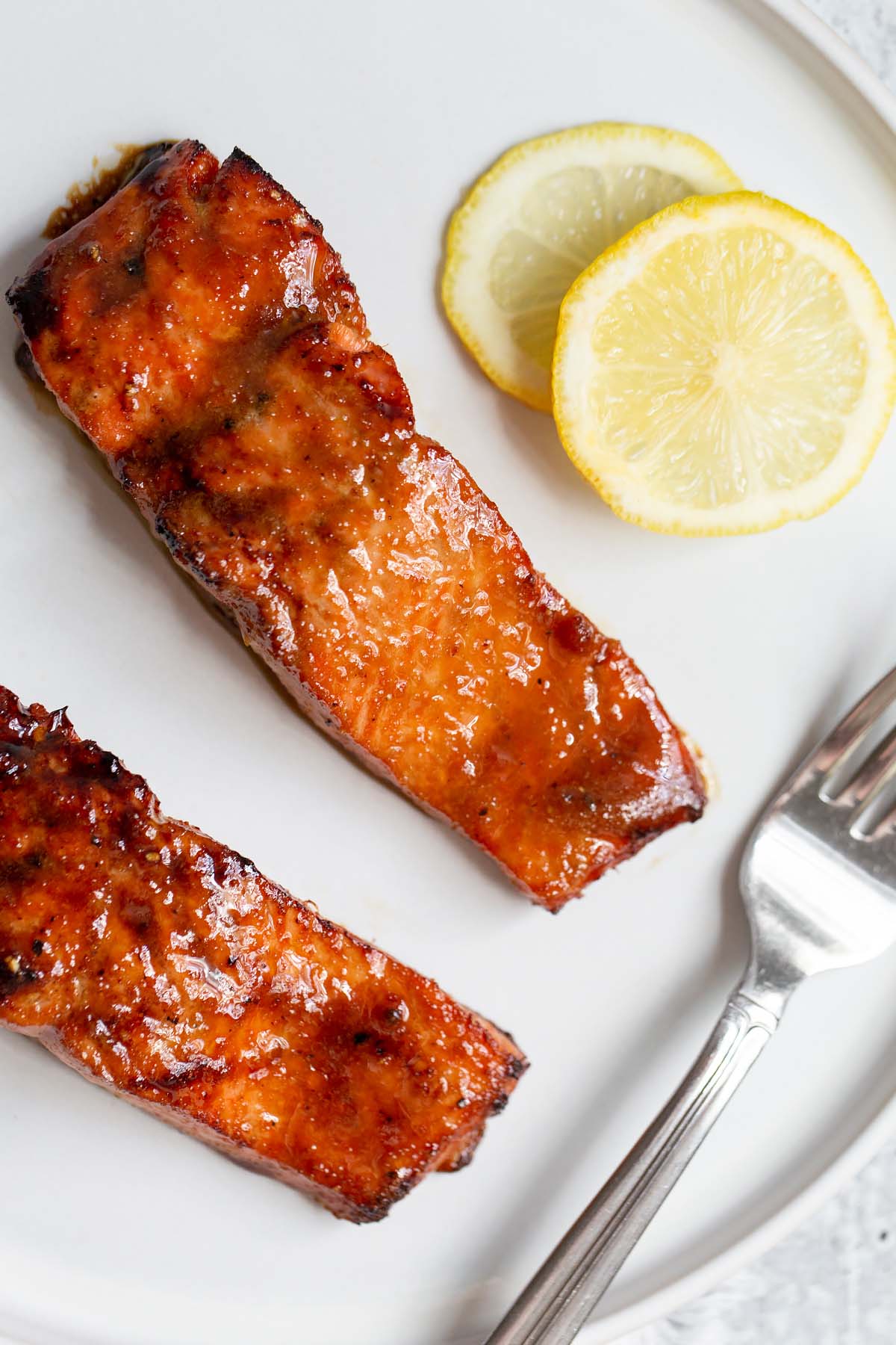 Two pieces of cooked salmon with lemon slices.