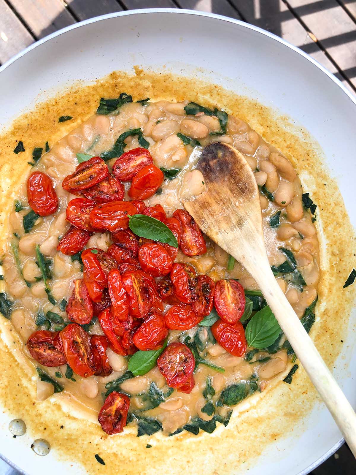 roasted tomatoes on top of cooked white beans in a skillet