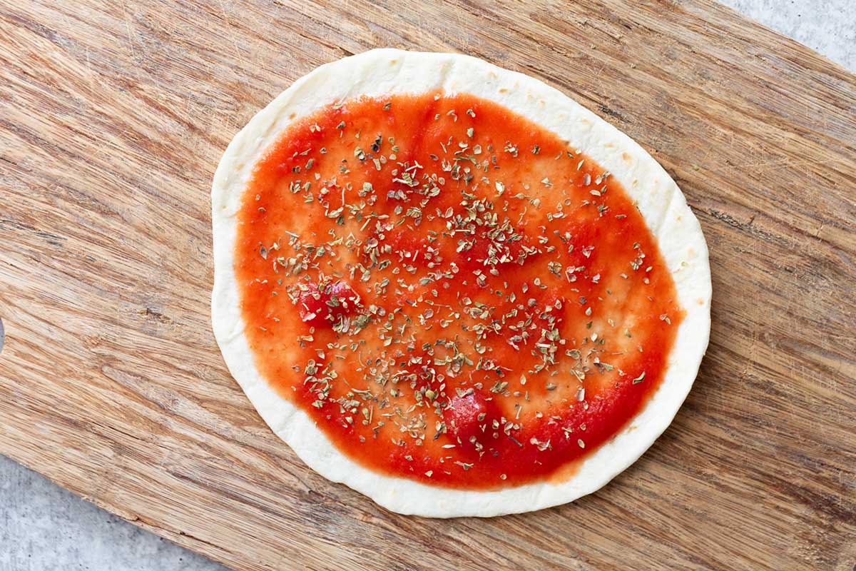 tortilla topped with tomato sauce and oregano