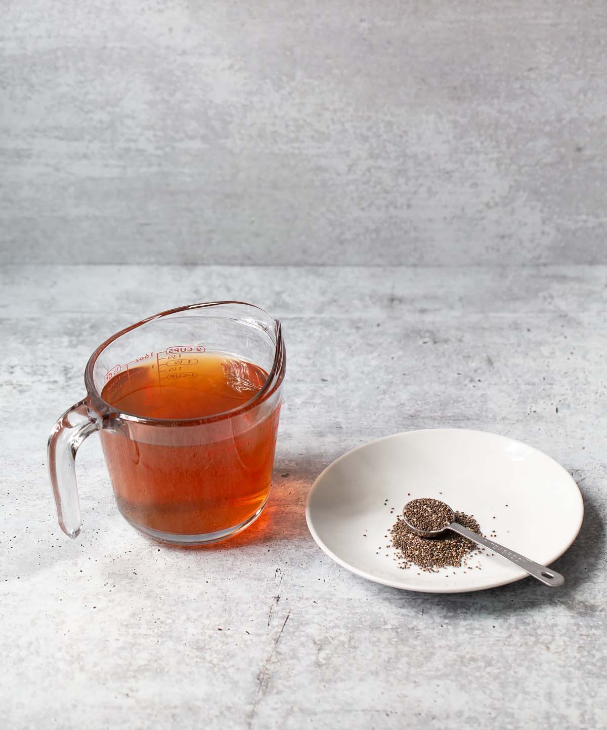 tea in a measuring cup and chia seeds on a plate