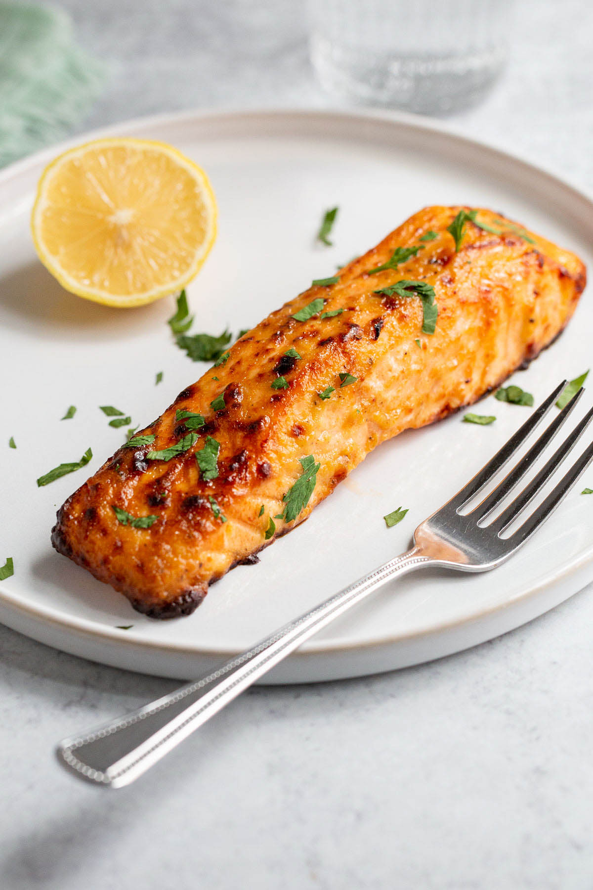 Air fryer honey mustard salmon on a plate with a lemon half.