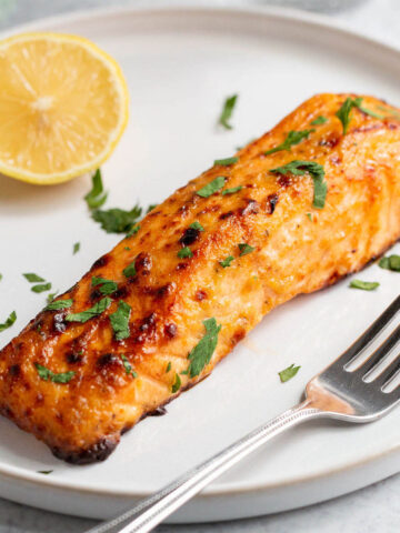 Air fryer honey mustard salmon on a plate with a lemon half.