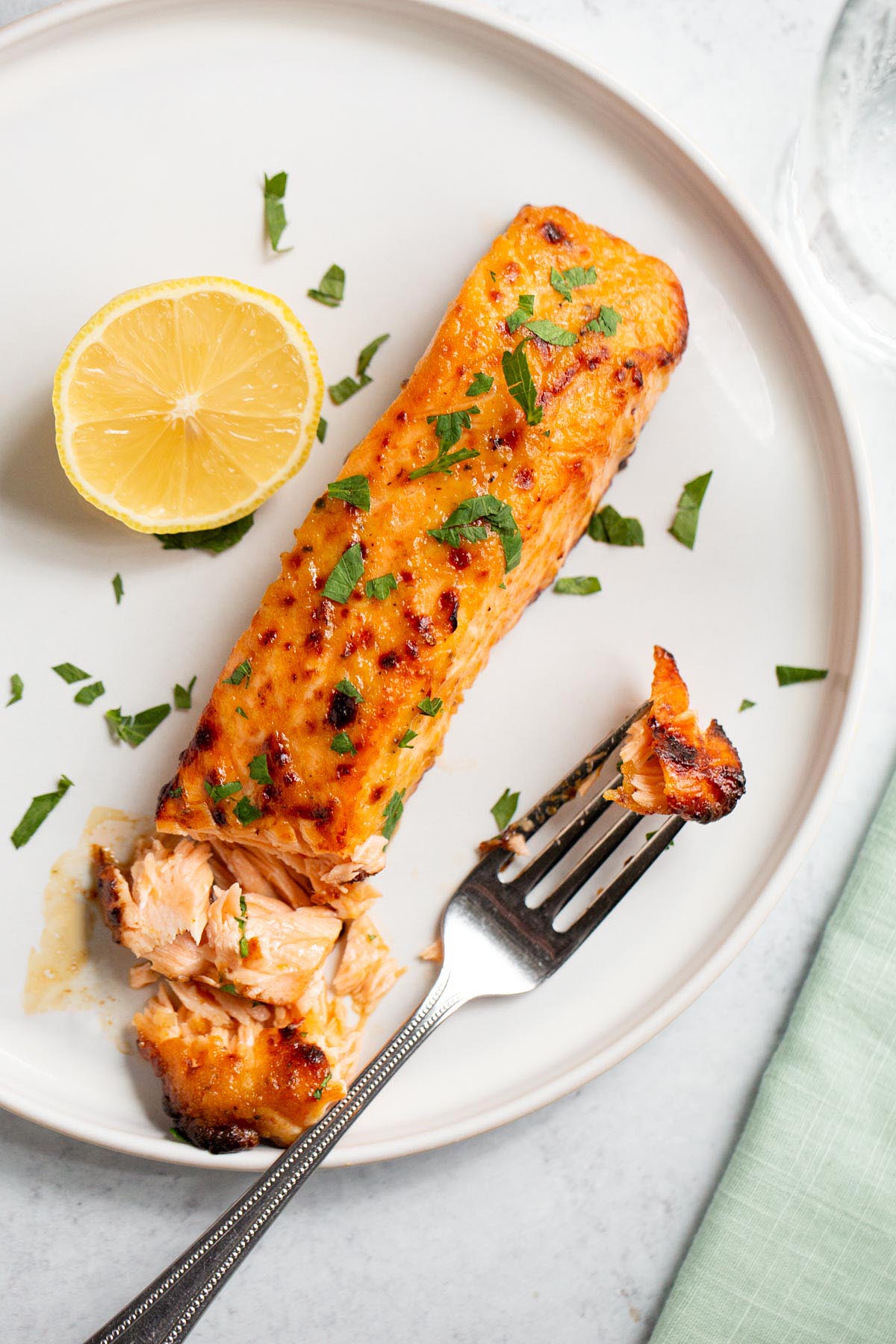 Air fryer honey mustard salmon on a plate with a lemon half.