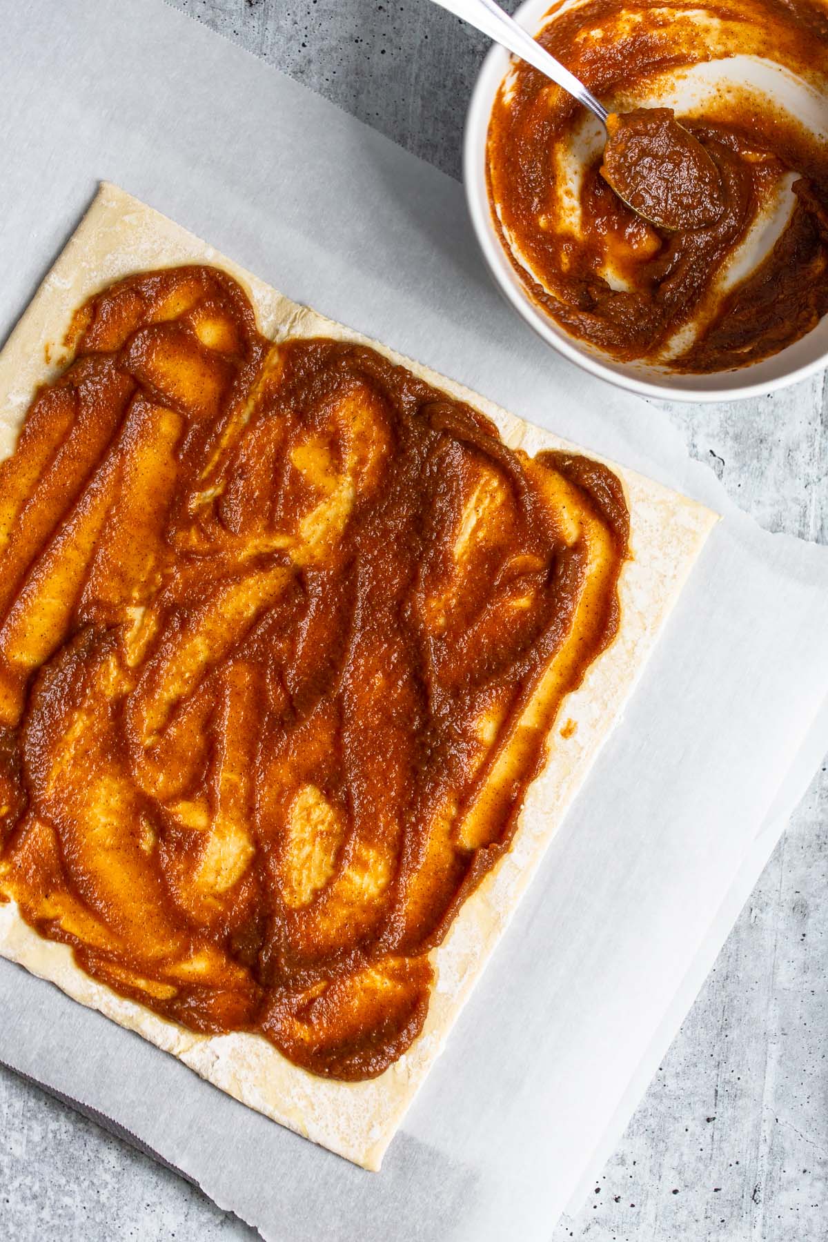 spreading pumpkin puree onto puff pastry