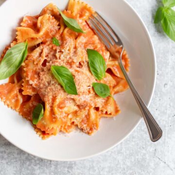 creamy harissa pasta topped with fresh basil leaves