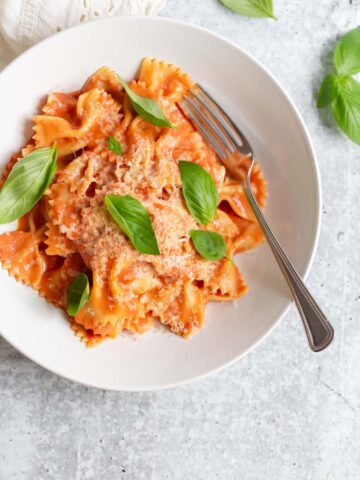 creamy harissa pasta topped with fresh basil leaves
