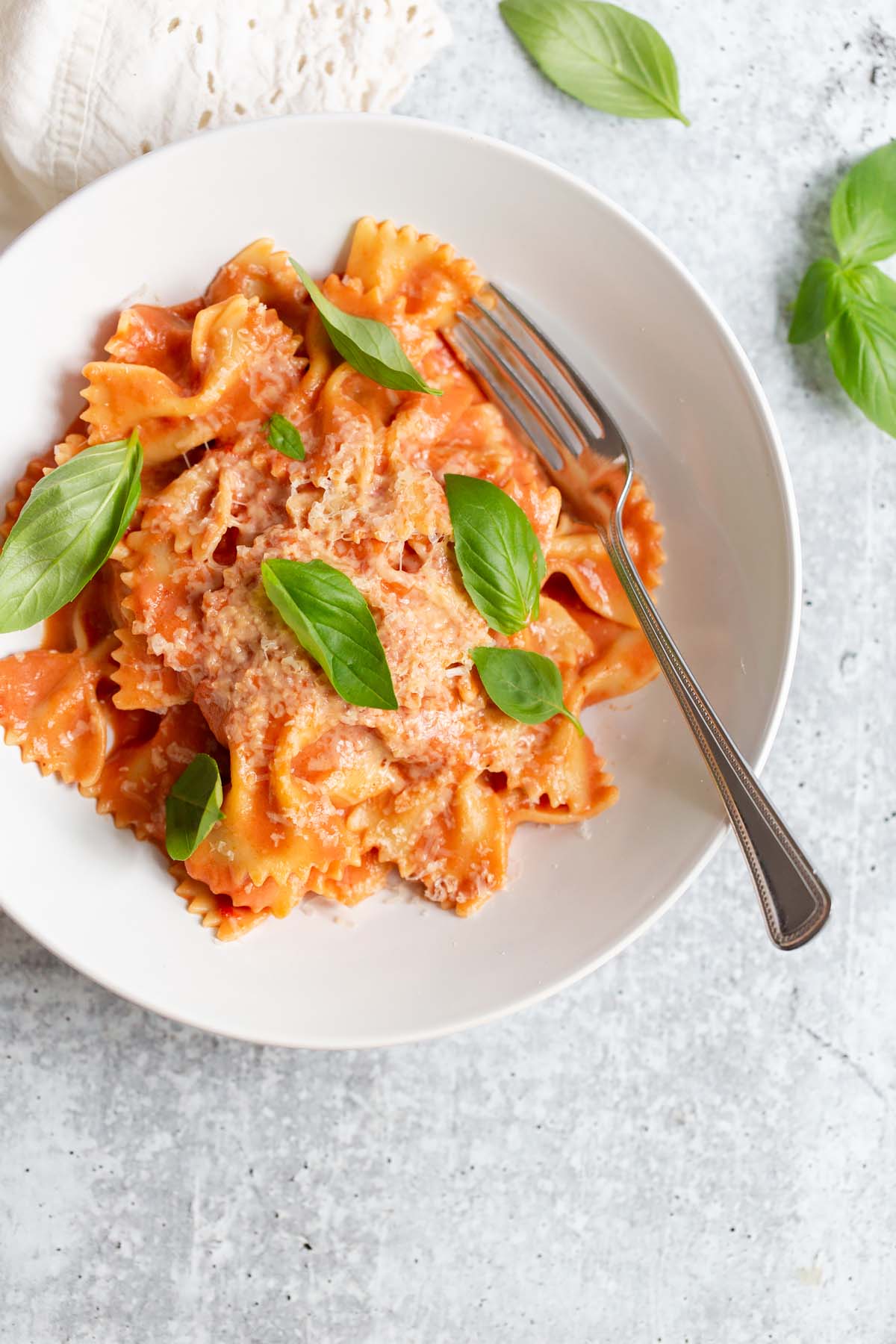 creamy harissa pasta topped with fresh basil leaves