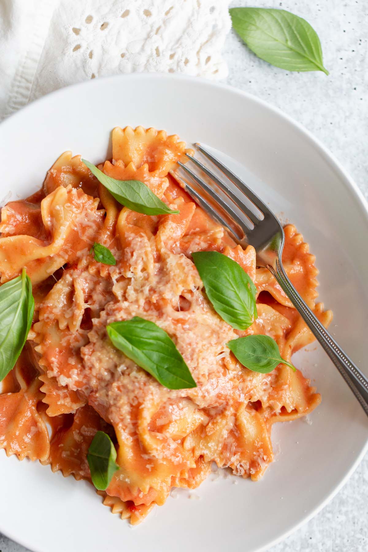 creamy harissa pasta topped with fresh basil leaves