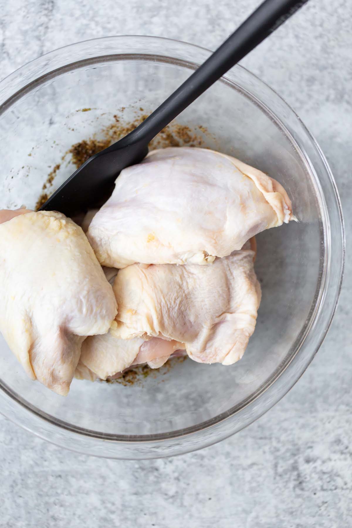 adding chicken thighs to marinade