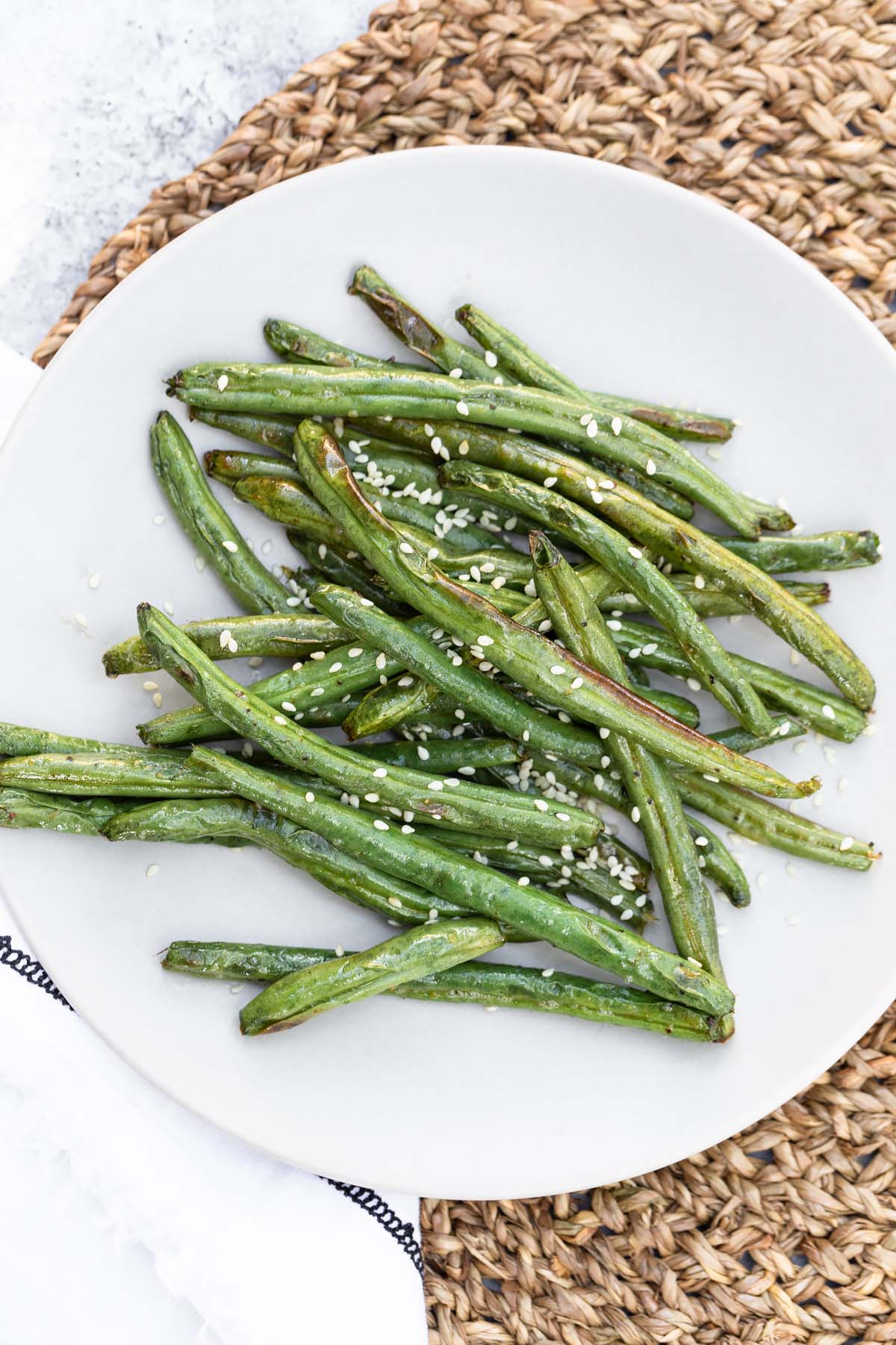 green beans on a plate topped with sesame seeds