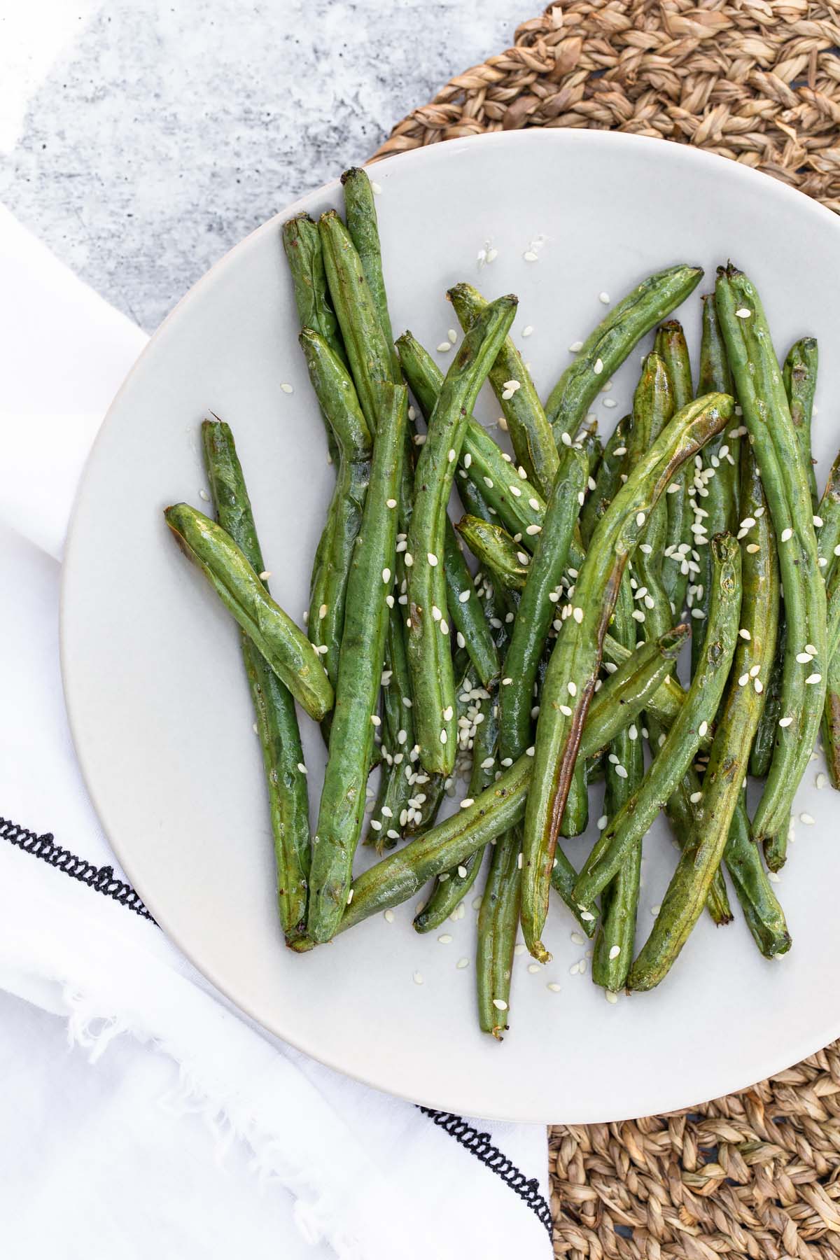 green beans on a plate topped with sesame seeds