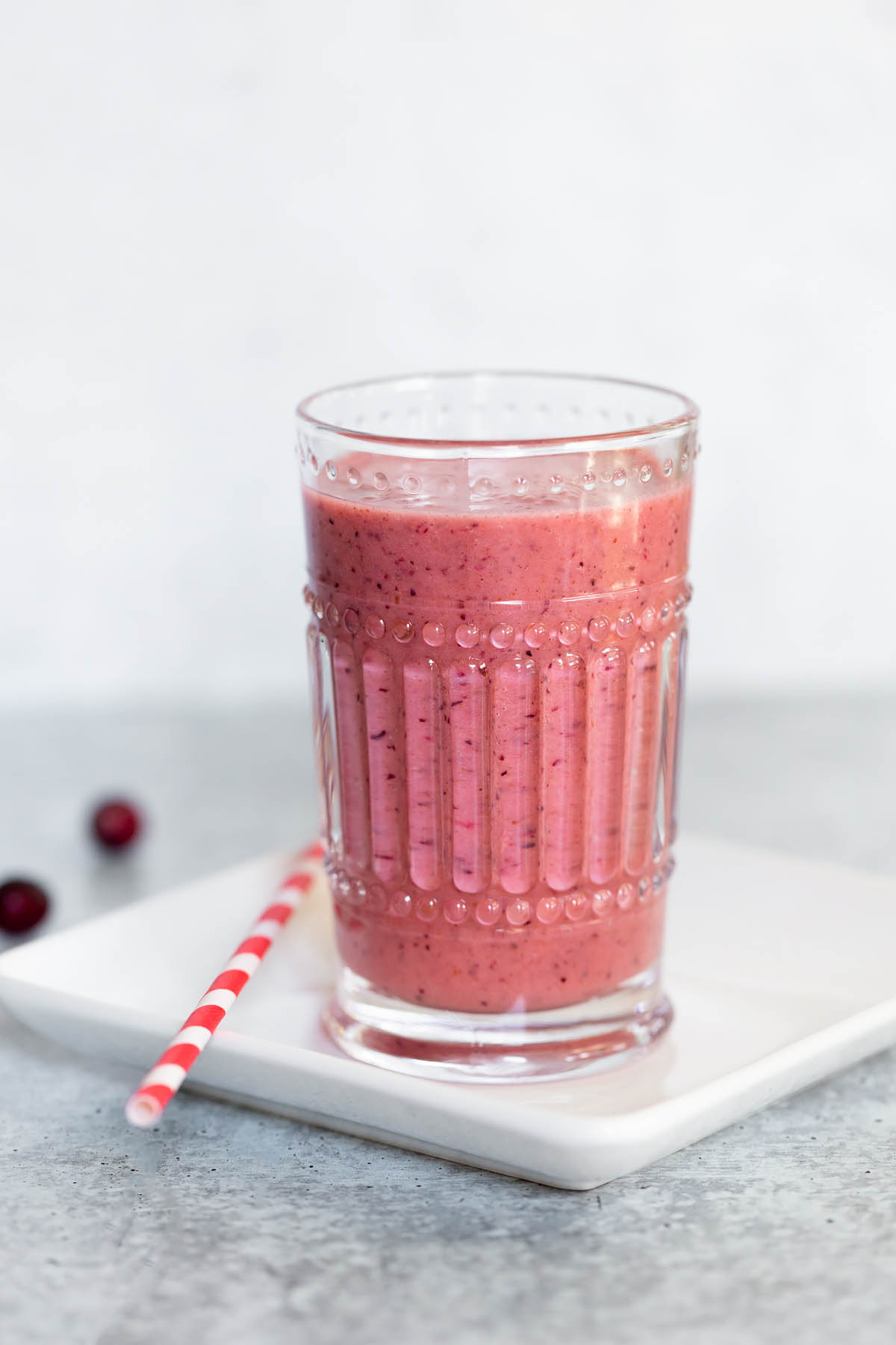 cranberry smoothie with a red and white straw on the side