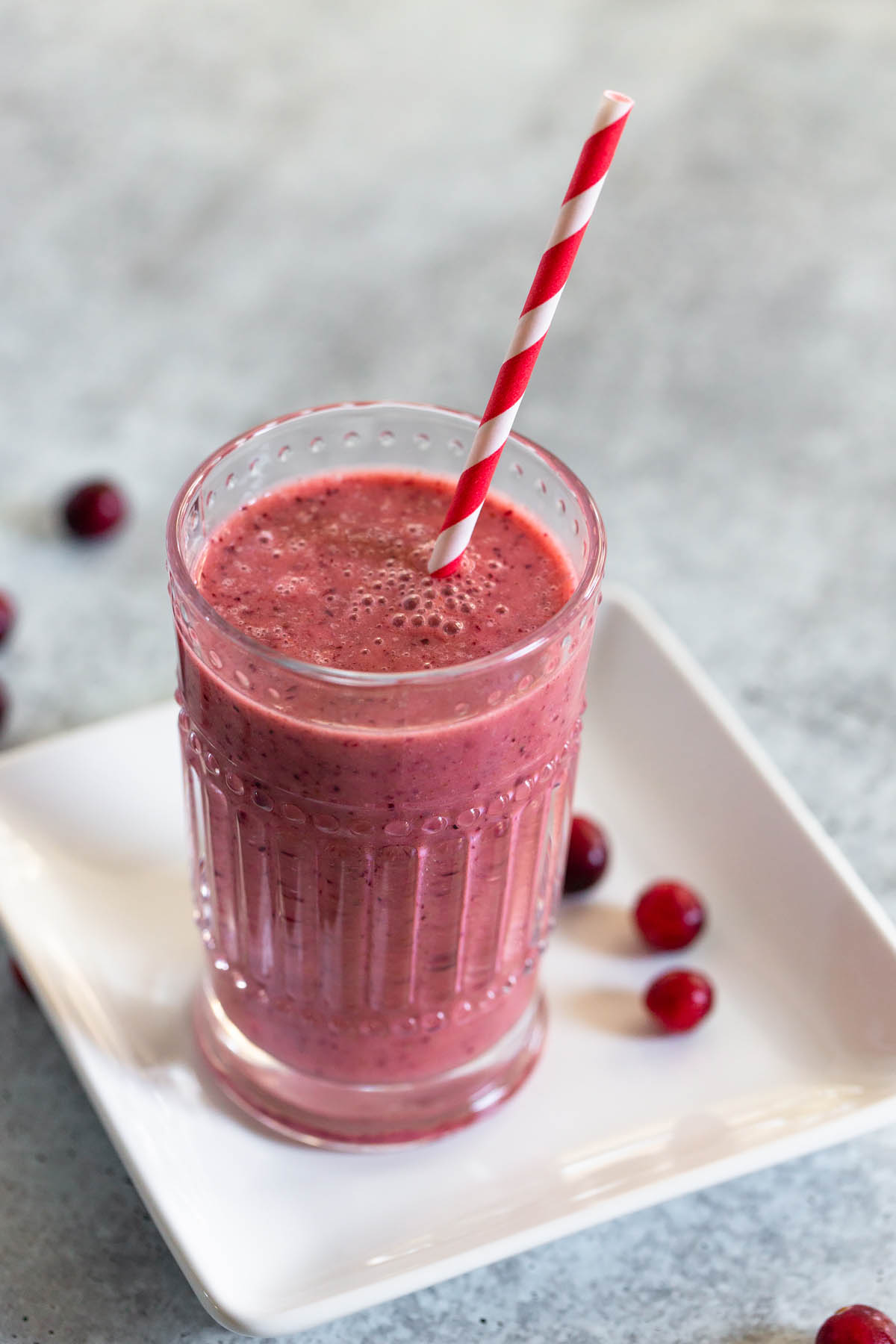 cranberry smoothie with a red and white striped straw