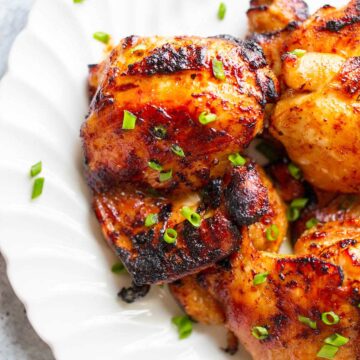 chicken thighs on a plate topped with green onions