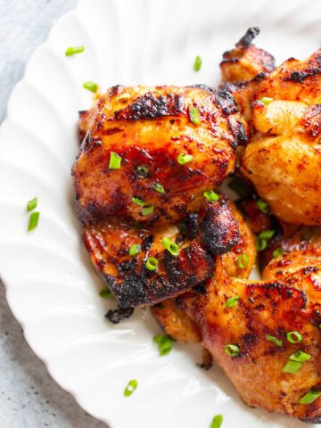 chicken thighs on a plate topped with green onions