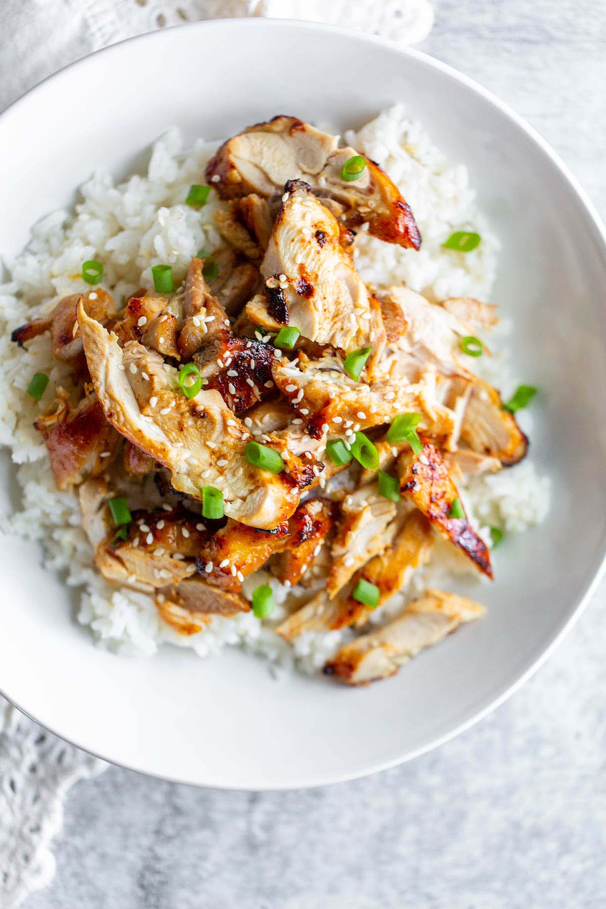 sliced chicken thighs served on top of a bed of rice topped with green onions